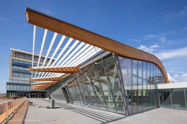 Moderne glazen gevel met houten en witte lamellen op het dak van het gebouw Bisonspoor.