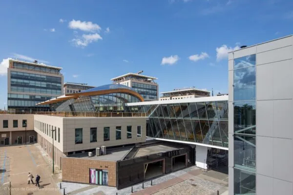 Modern gebouw met glazen loopbrug en ingang van winkelcentrum Bisonspoor in Maarssen.