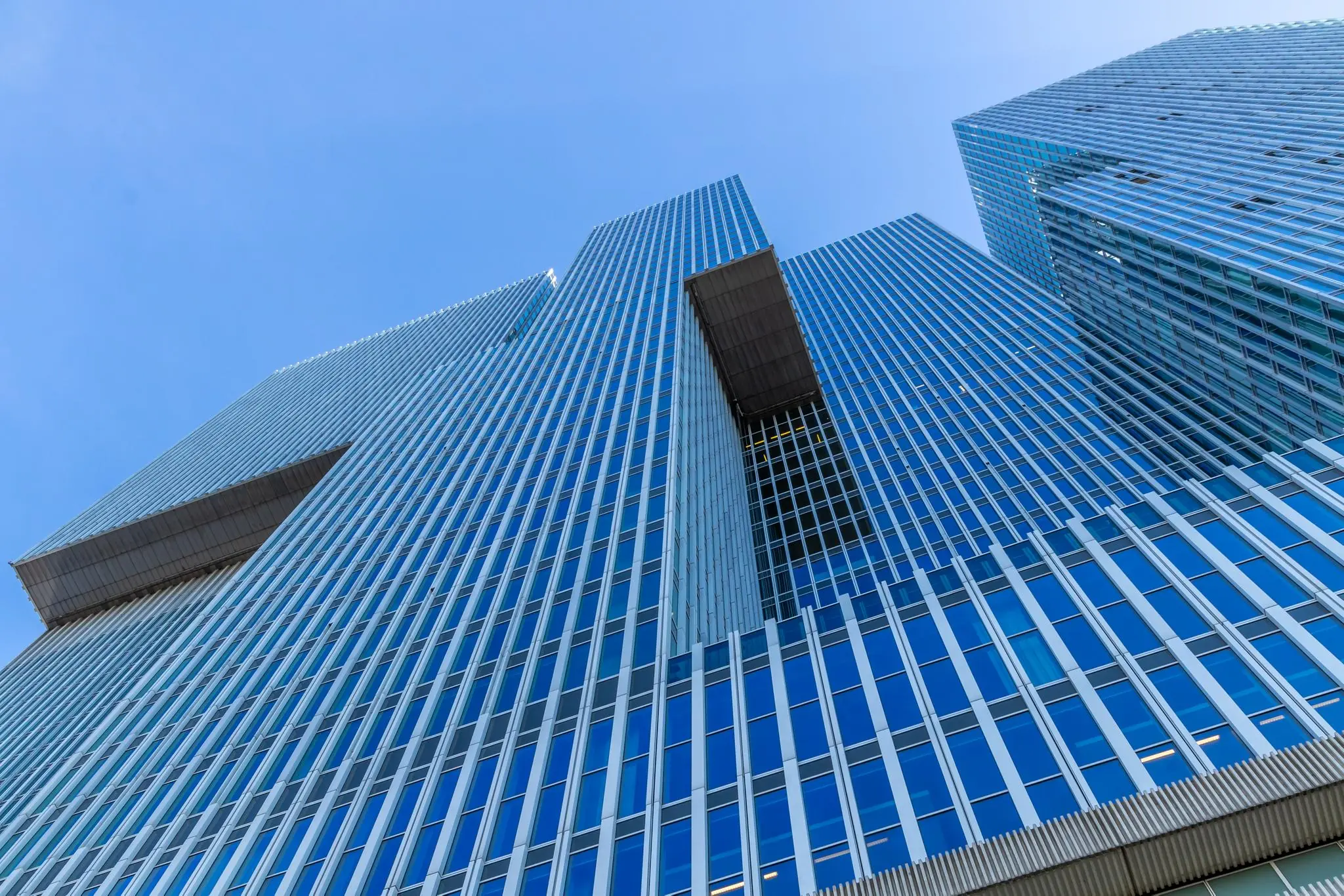 Modern hoog gebouw met glazen gevel aan de Wilhelminakade in Rotterdam, gezien van onderaf tegen een blauwe lucht.