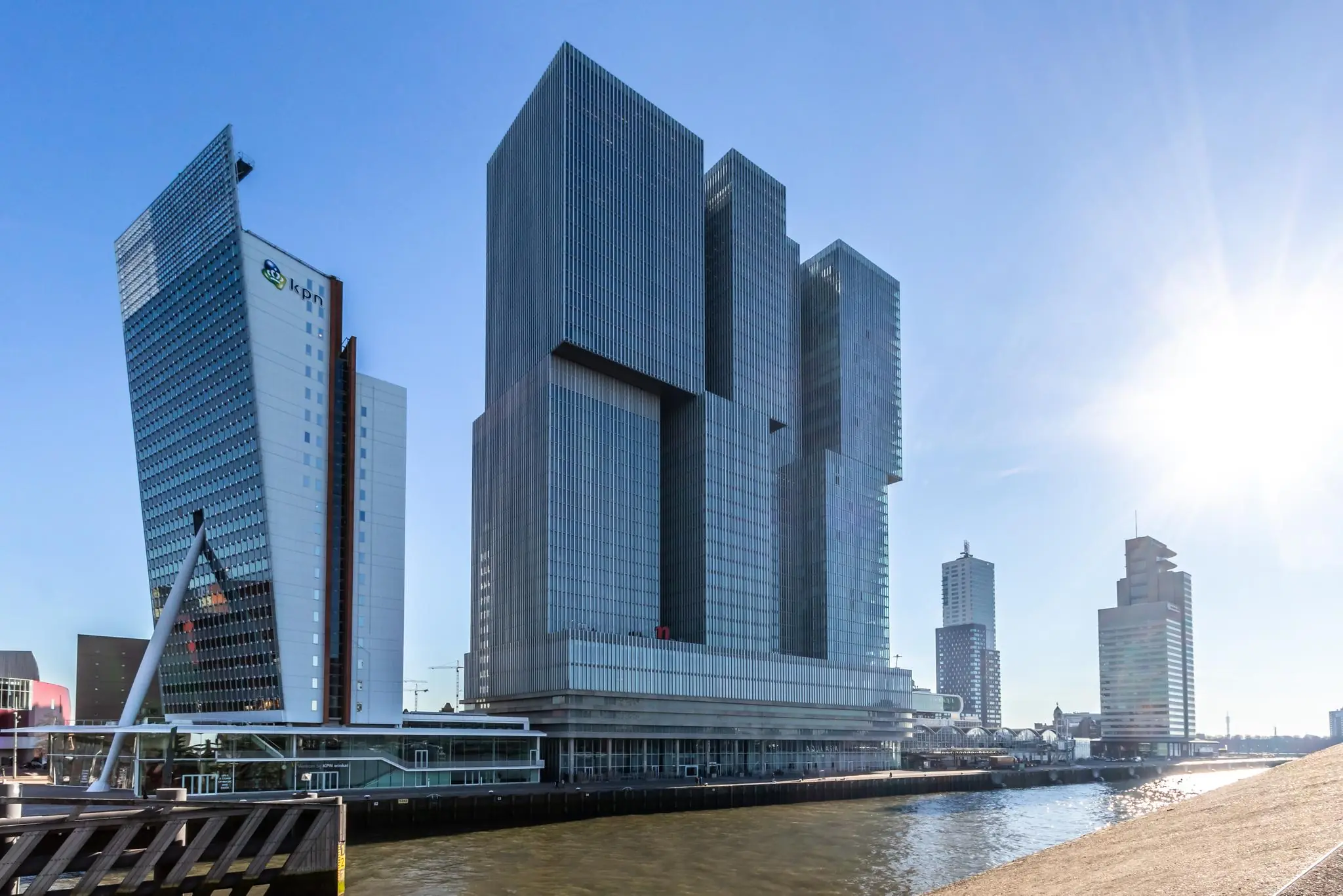 Moderne hoogbouw aan de Wilhelminakade in Rotterdam met de zon laag aan de hemel.