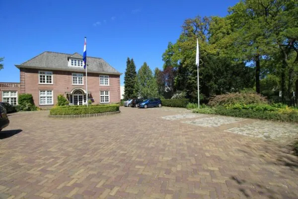 Vooraanzicht van een statig bakstenen kantoorpand aan de Amersfoortsestraat met een Nederlandse vlag en een ruime parkeerplaats.
