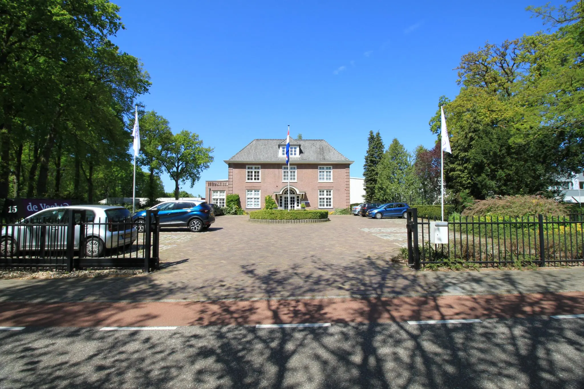 Vooraanzicht van een statig, vrijstaand herenhuis aan de Amersfoortsestraat met een oprijlaan, geparkeerde auto's en Nederlandse vlag.