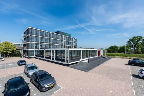Modern kantoorgebouw aan de Lindtsedijk met glazen gevel en naastgelegen parkeerterrein.