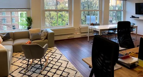 Modern ingericht kantoor aan de Keizersgracht met zithoek, werkplekken en grote ramen met uitzicht op de gracht.