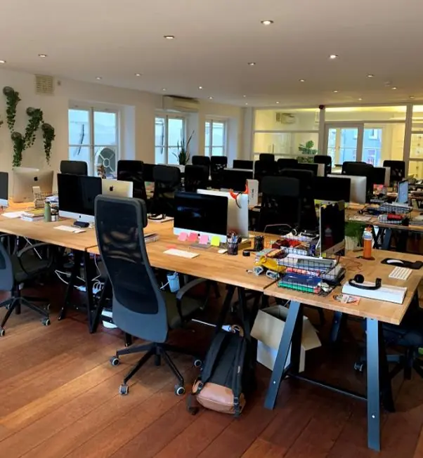 Moderne kantoortuin aan de Keizersgracht met lange houten bureaus, computerschermen en bureaustoelen.