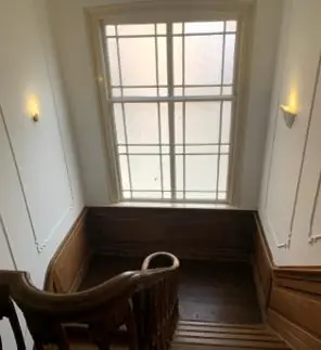 Houten trap met klassieke leuning en grote raam in een pand aan de Keizersgracht.