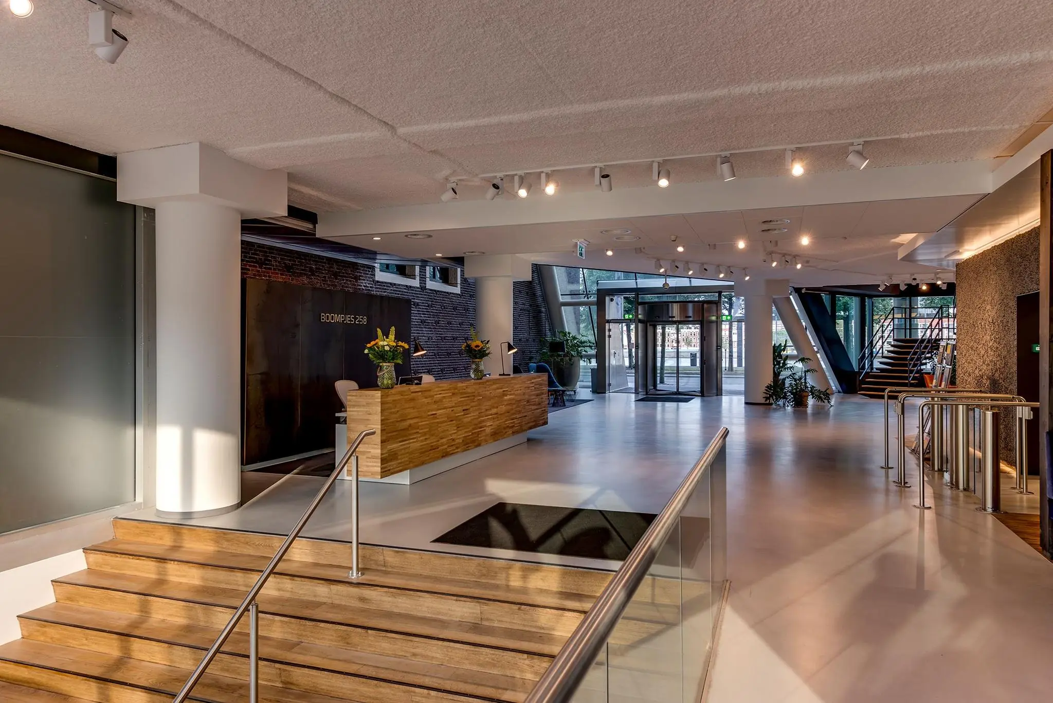 Moderne ontvangsthal met houten receptiebalie bij de ingang van Boompjes 258.