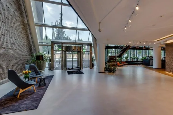 Moderne en lichte entreehal van een kantoorpand aan de Boompjes met glazen gevel, zitgedeelte en trap naar de bovenverdieping.