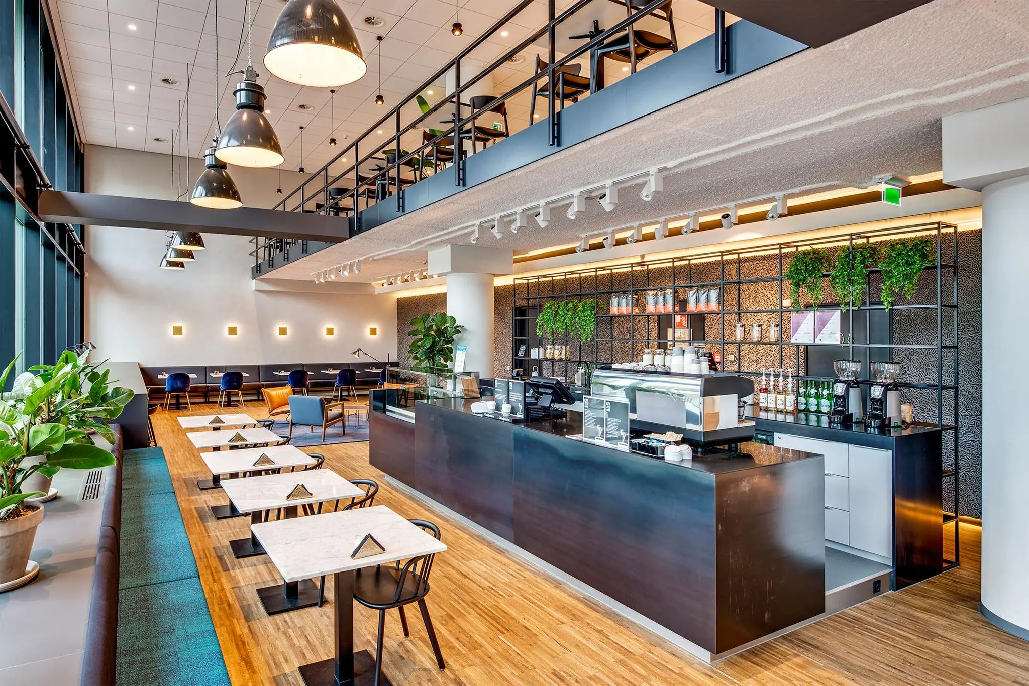 Modern ingerichte koffiebar Boompjes met hoge plafonds, strakke meubels en een open mezzanine.