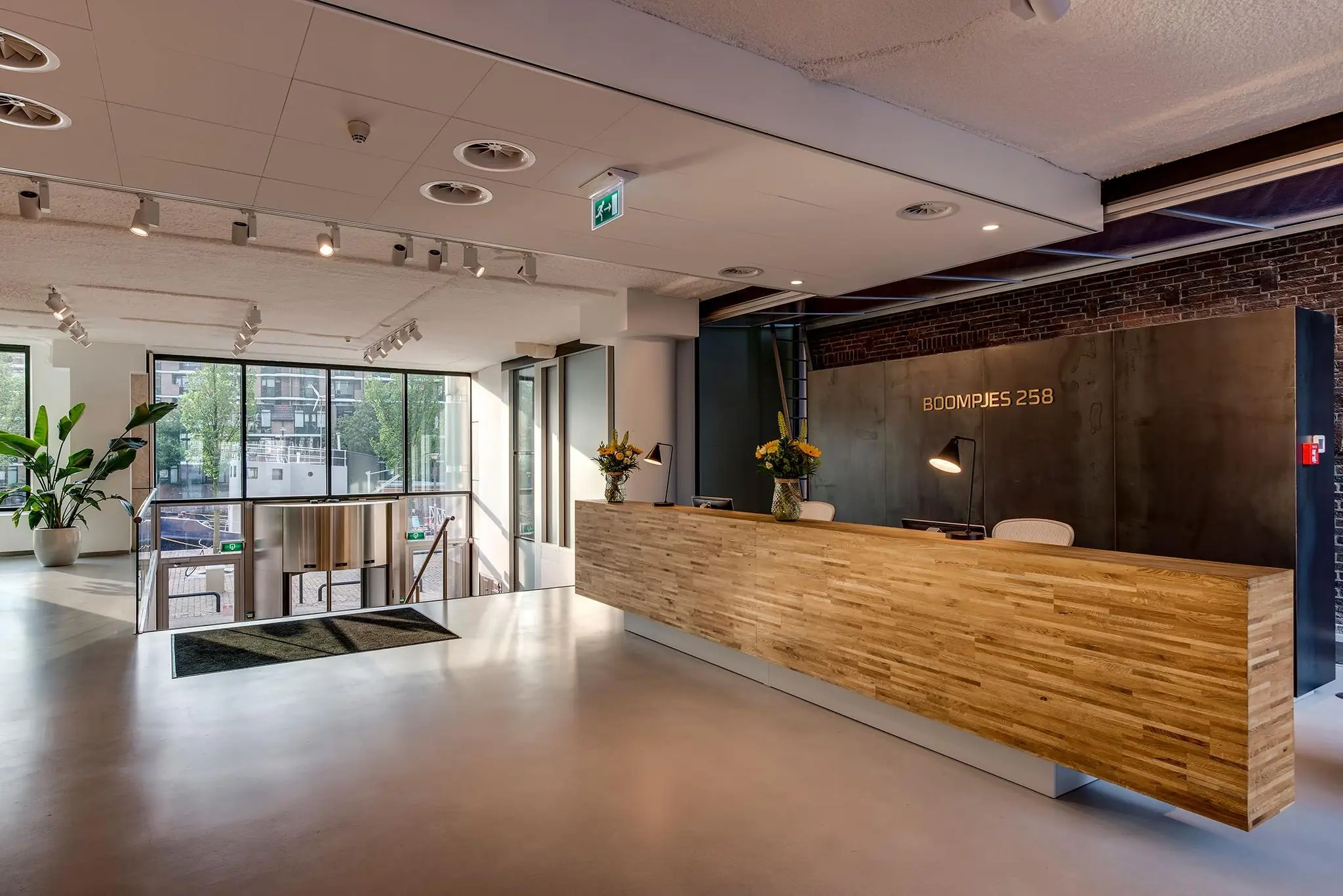 Moderne ontvangsthal met houten balie en het adres 'Boompjes 258' op de achterwand.