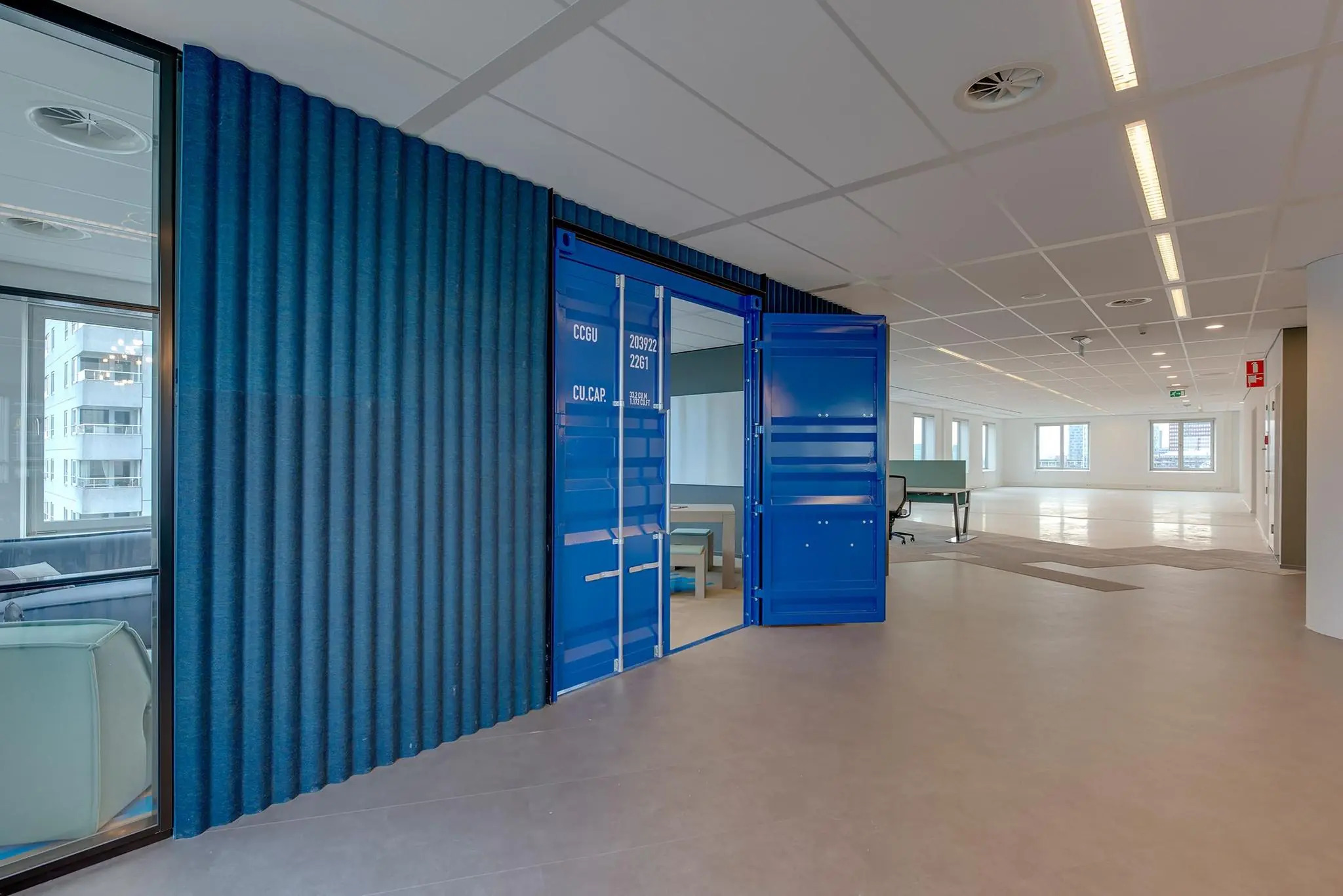 Modern kantoorinterieur met een opvallende vergaderruimte in de vorm van een blauwe zeecontainer.