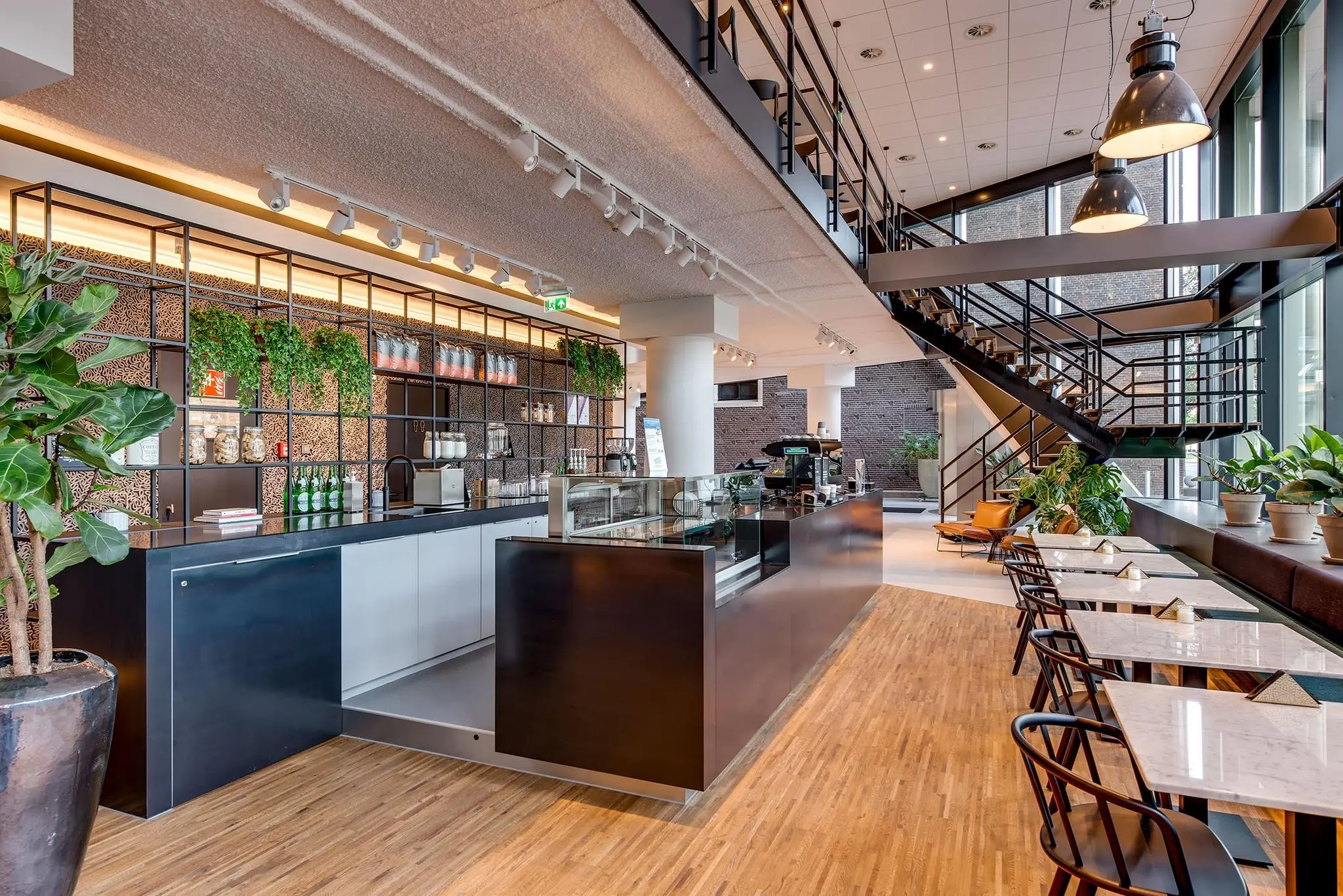 Modern ingericht café met open trap en veel groen aan de Boompjes in Rotterdam.
