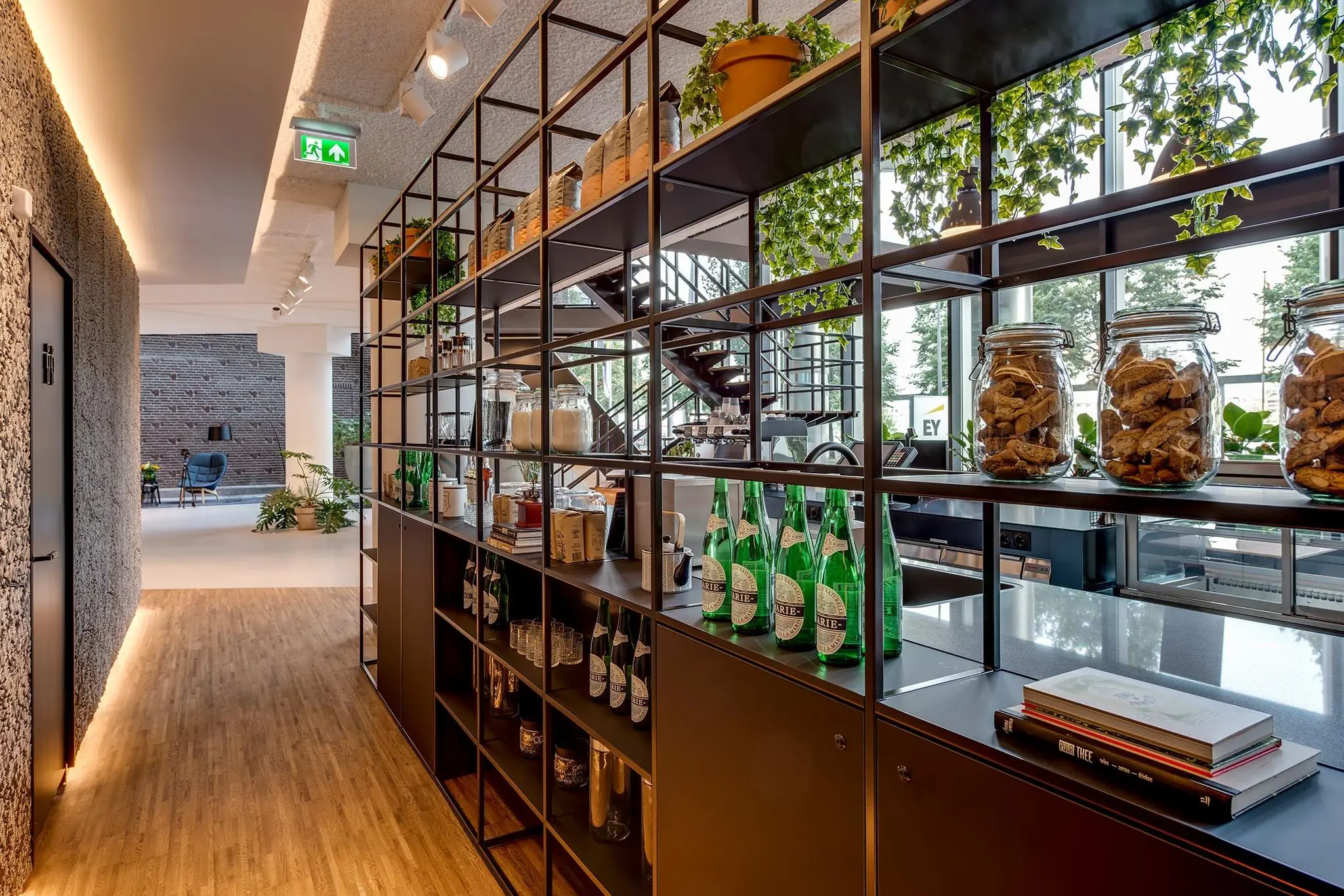 Moderne open kast in een stijlvol kantoorinterieur met glazen flessen, potten en groene planten bij Boompjes 60 in Rotterdam.