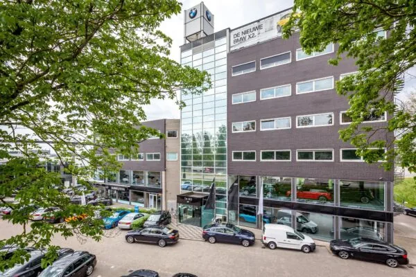 Vooraanzicht van een modern kantoorgebouw aan de Mijlweg met BMW-showroom en geparkeerde auto's.