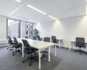 Moderne, lichte kantoorruimte met meerdere bureaus en ergonomische bureaustoelen.