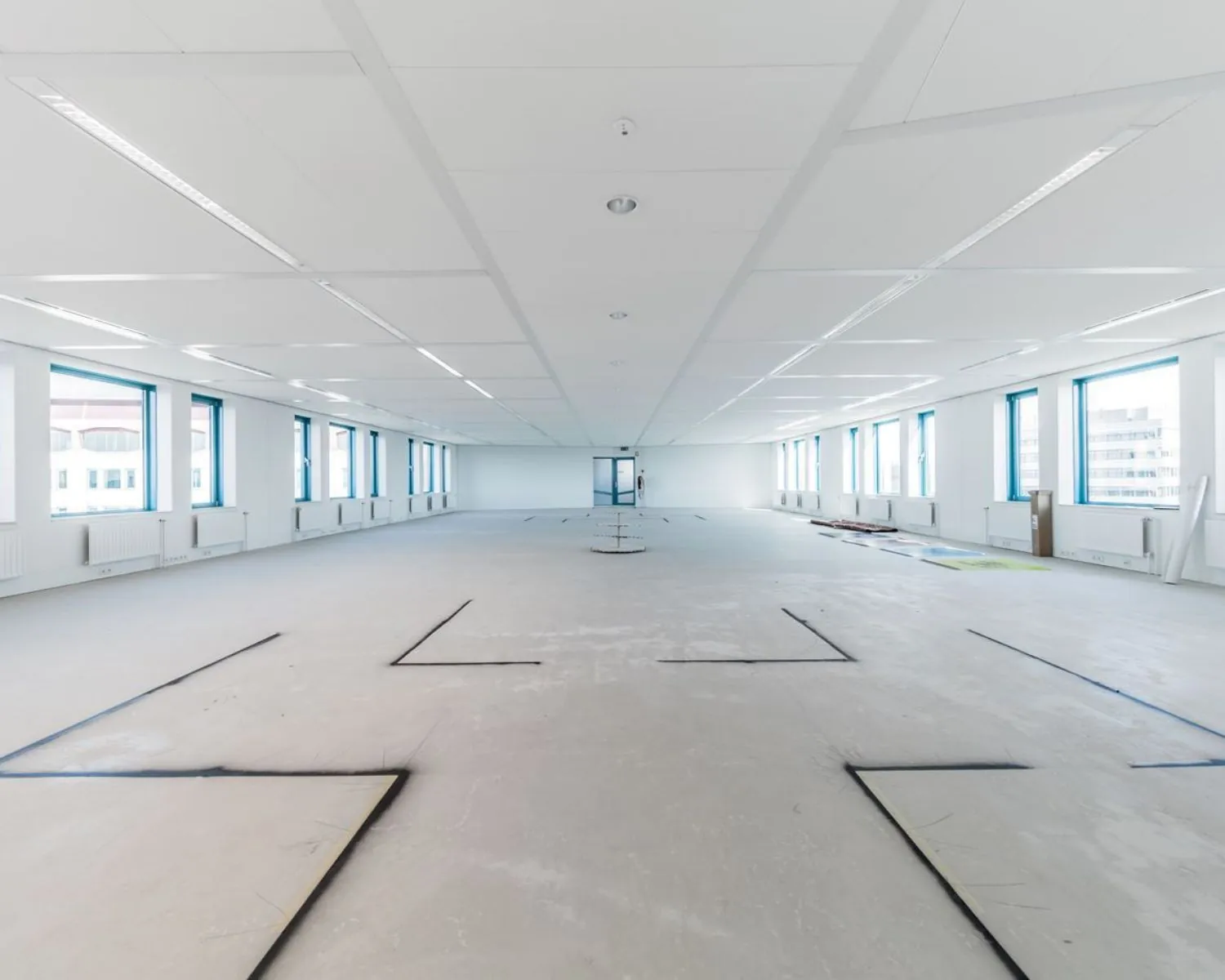 Leeg, ruim en licht kantoorinterieur met zichtbare vloerindelingen voor toekomstige werkplekken.