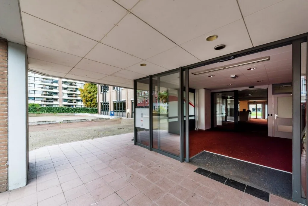 Ingang van een kantoorpand aan de Meesterlottelaan met glazen schuifdeuren en rode vloerbedekking binnen.