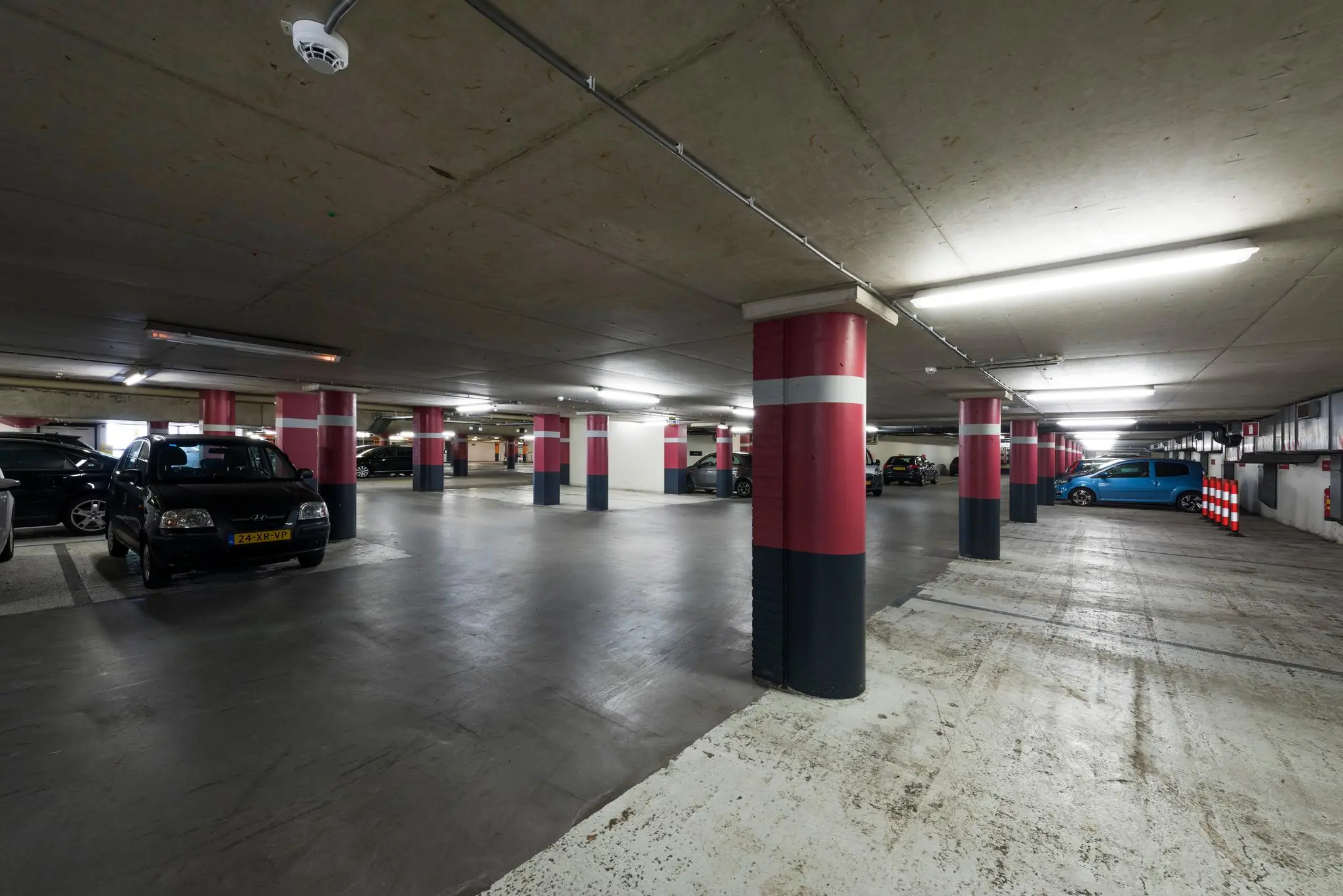 Ondergrondse parkeergarage aan de Meesterlottelaan met meerdere geparkeerde auto's en rood-wit-zwarte pilaren.