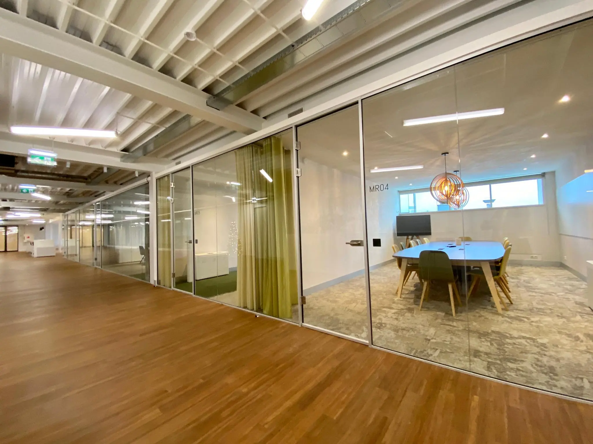 Moderne kantoorruimte aan het Bisonspoor met glazen vergaderruimtes en houten vloer.