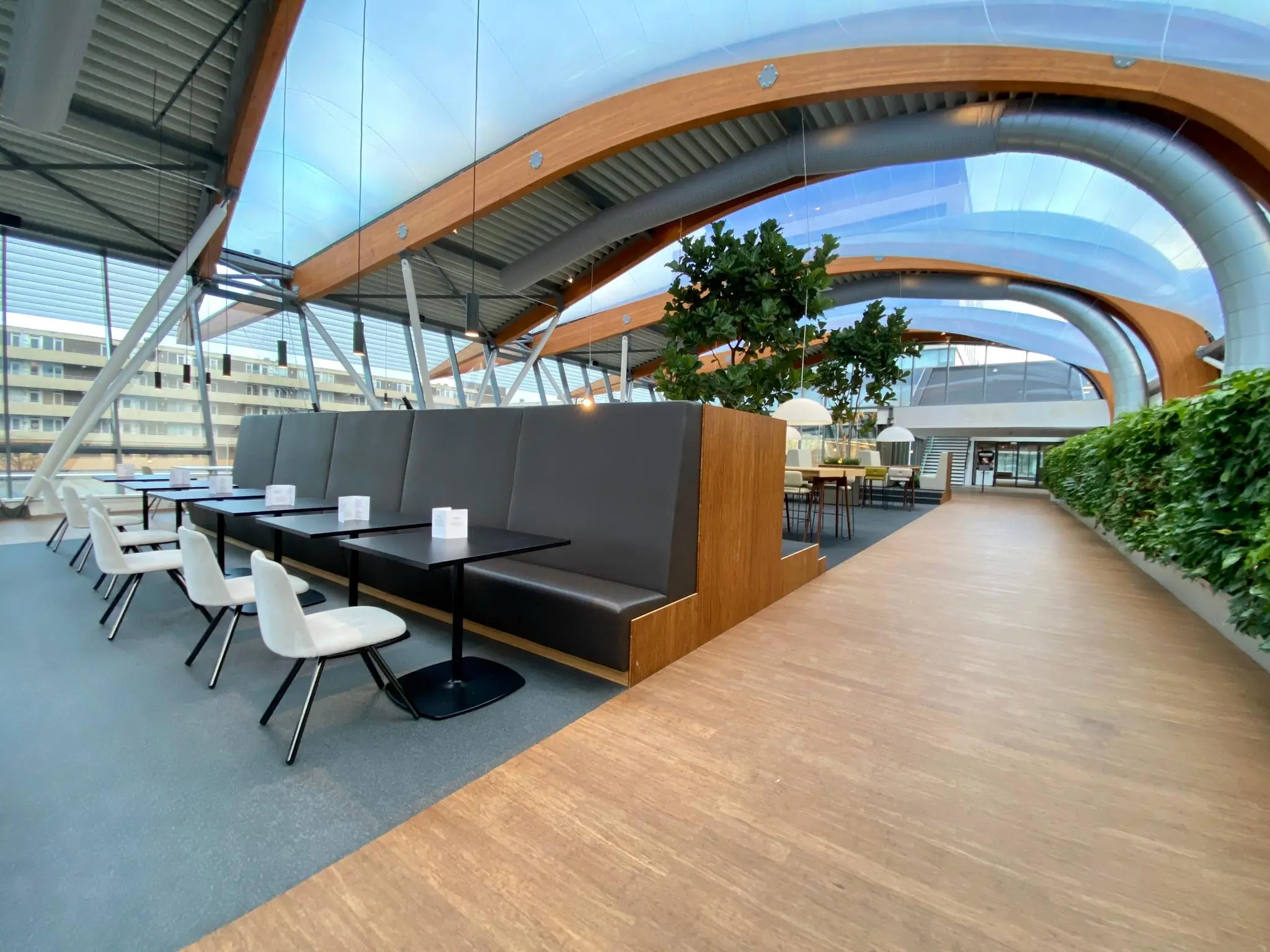 Moderne en lichte zitruimte in het gebouw Bisonspoor met hoge plafonds, houten accenten en veel groen.