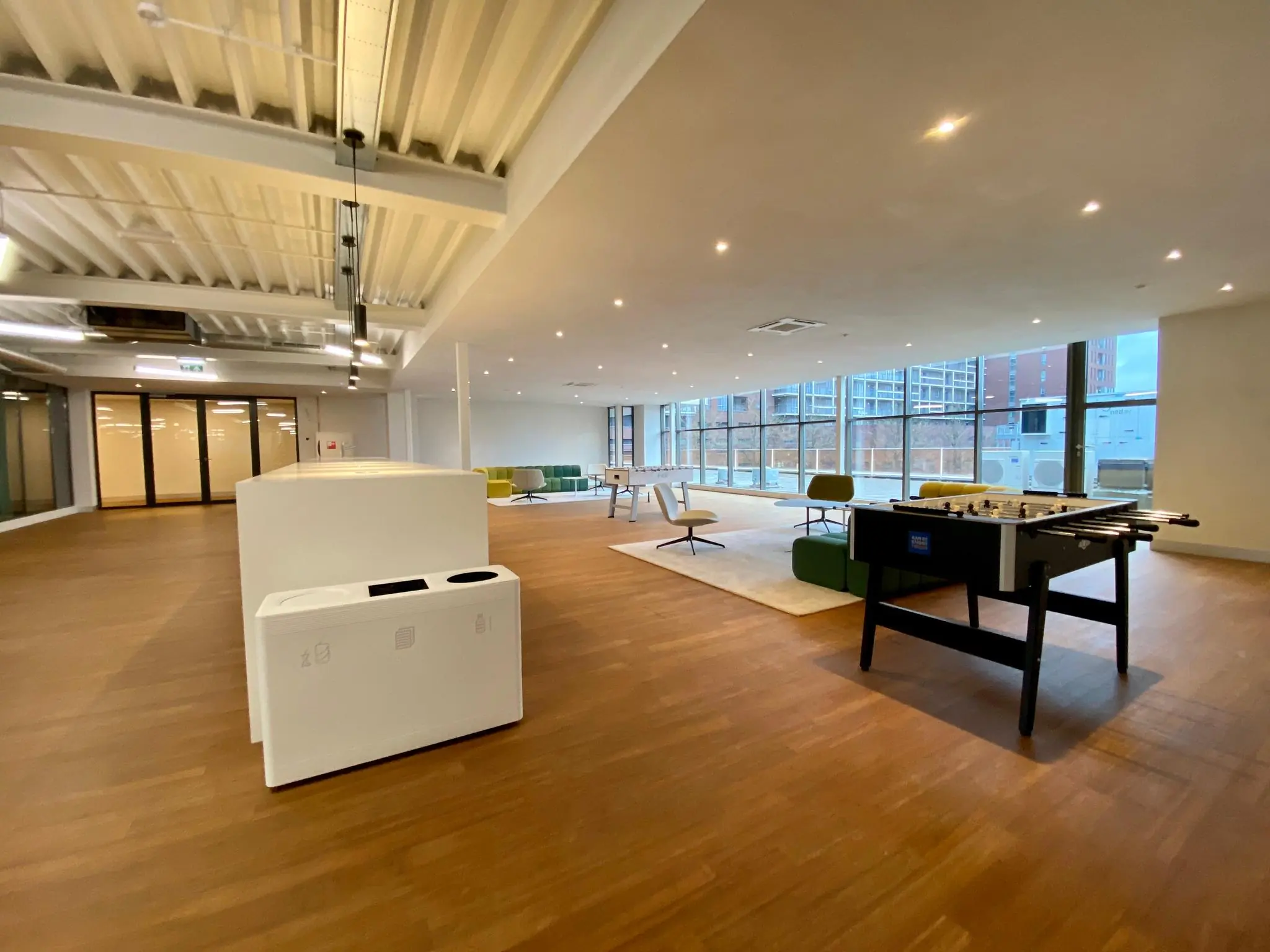 Moderne kantoorruimte aan het Bisonspoor met zithoek, tafelvoetbaltafel en grote ramen.