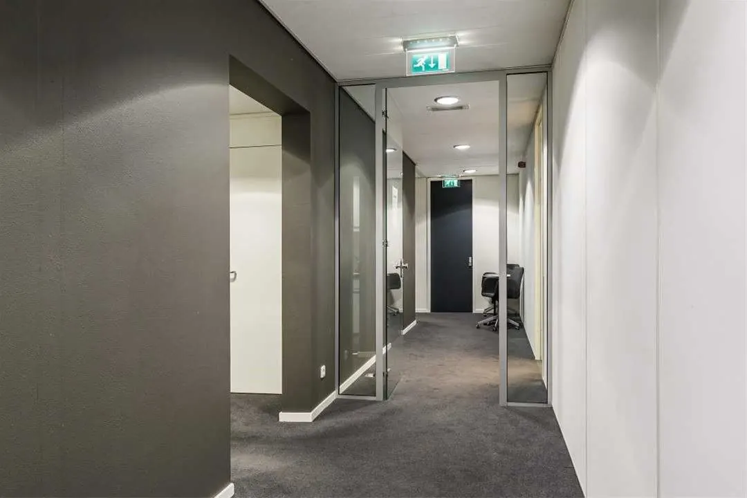 Moderne kantoorruimte aan de Savannahweg met glazen wanden, grijze vloeren en een open deur naar vergaderruimte.