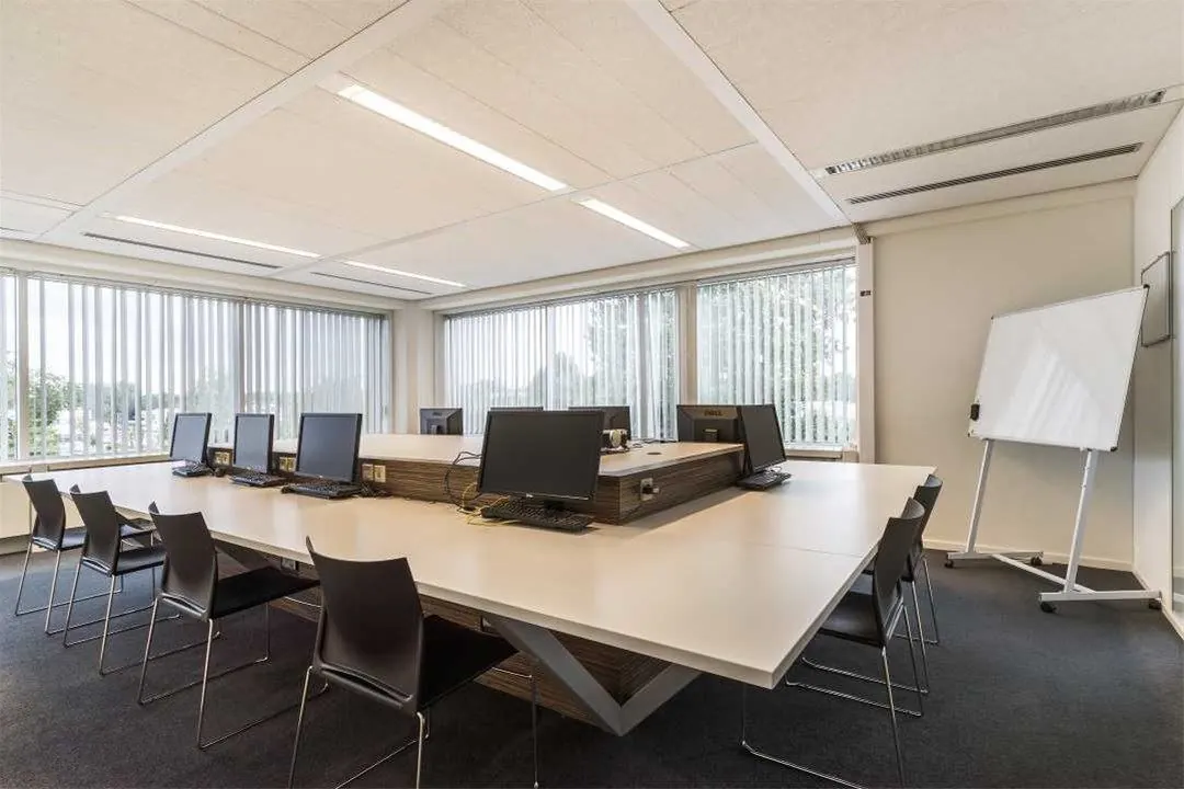 Moderne kantoorruimte aan de Savannahweg met grote werktafel, computers, stoelen en een whiteboard bij het raam.