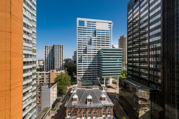 Uitzicht op de Blaak in Rotterdam met een mix van moderne hoogbouw en een historisch pand op de voorgrond.
