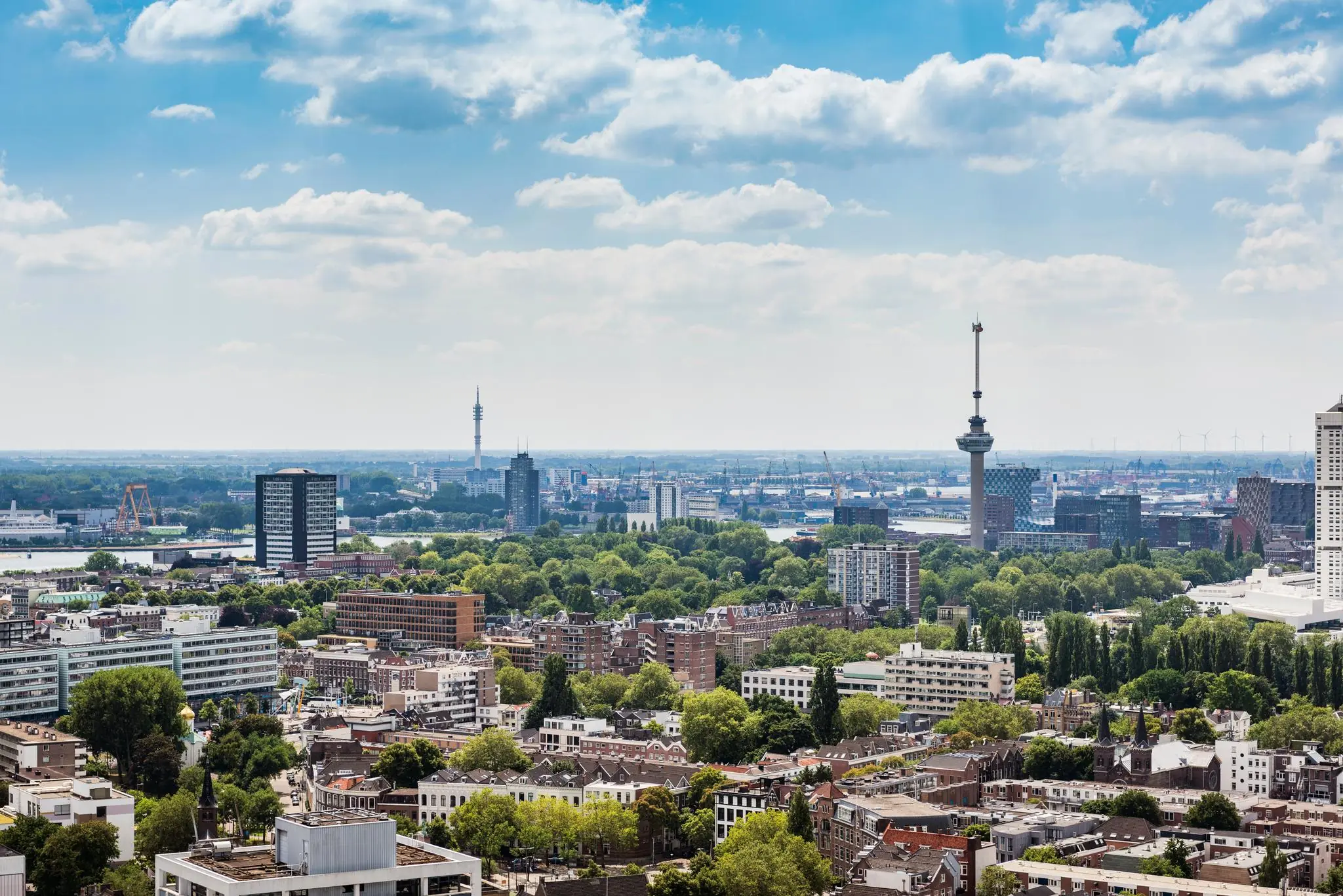 Stedelijk uitzicht op Rotterdam met de Euromast prominent in beeld op een zonnige dag.
