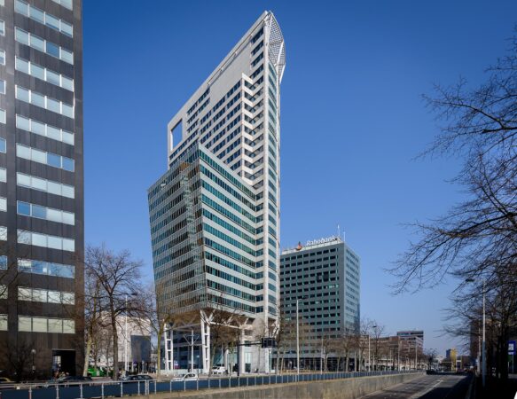 Hoogbouw aan de Blaak in Rotterdam met het opvallende kantoorgebouw The Red Apple en het Rabobank-gebouw onder een heldere blauwe lucht.