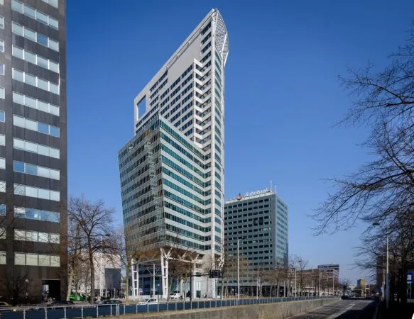 Hoogbouw aan de Blaak in Rotterdam met het opvallende kantoorgebouw The Red Apple en het Rabobank-gebouw onder een heldere blauwe lucht.