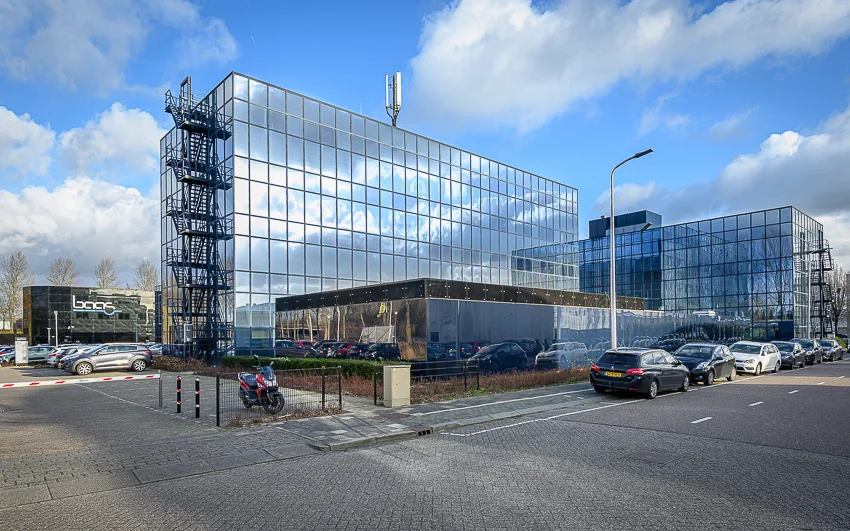 Glazen kantoorgebouwen aan de Esserbaan in een moderne bedrijfsomgeving met geparkeerde auto’s op de voorgrond.