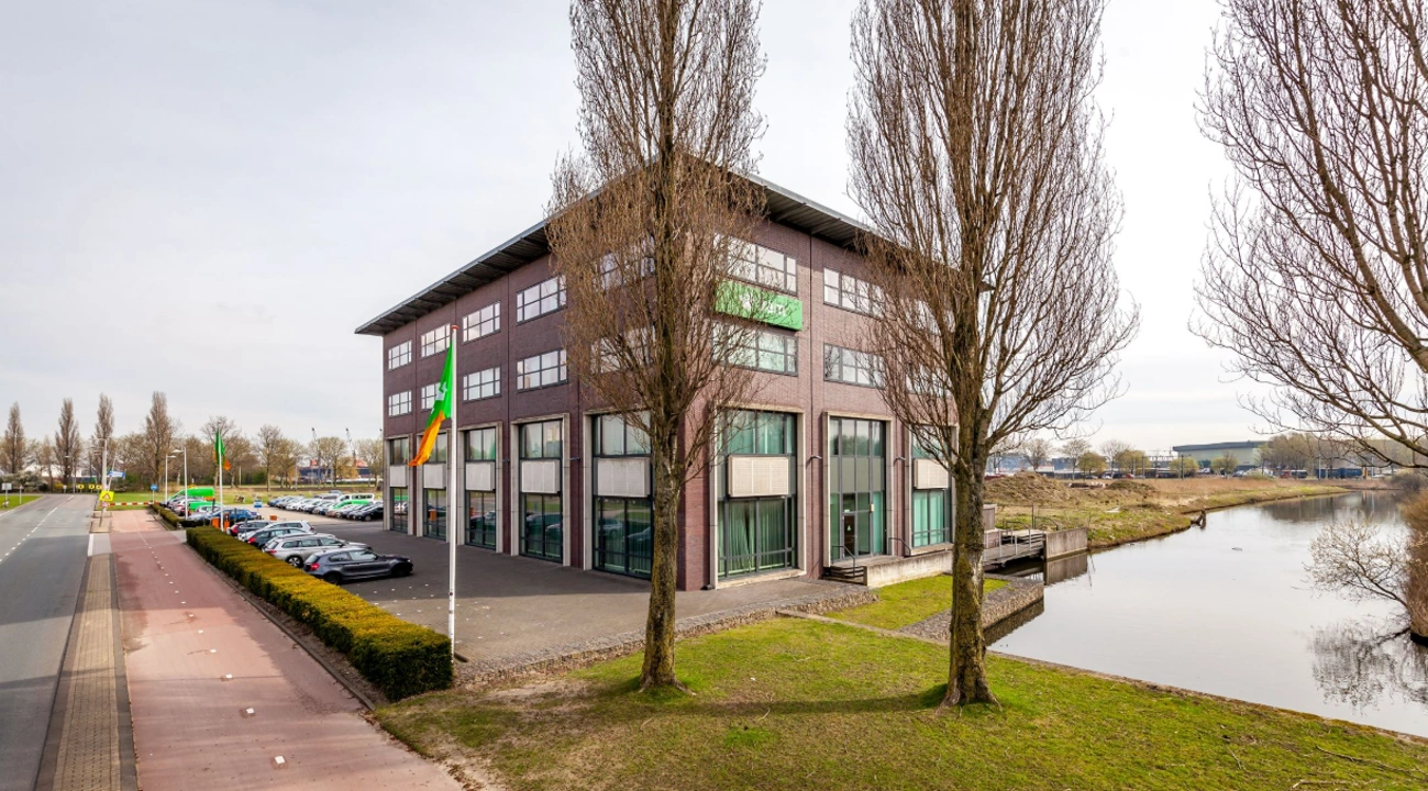 Kantoorgebouw aan de Contactweg met parkeerplaats en waterpartij op de voorgrond.