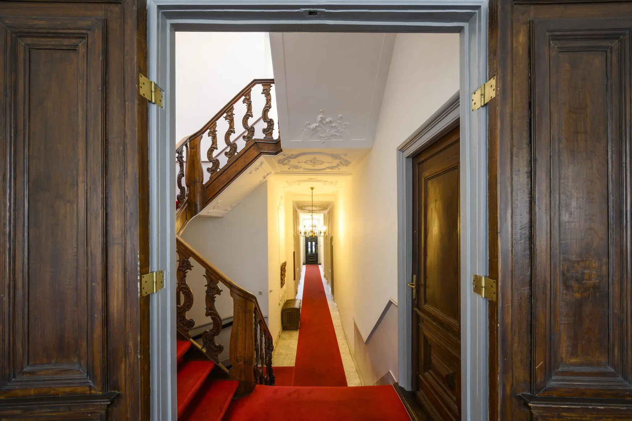 Doorkijk in een karakteristiek grachtenpand aan de Keizersgracht met een houten trap, sierplafond en rode loper in de gang.