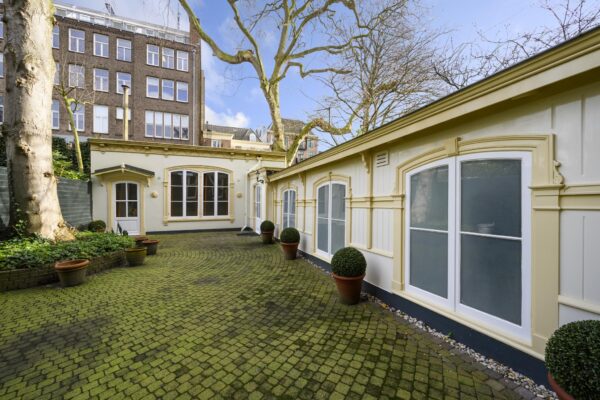 Binnenplaats met klassieke gevels en groen betegelde bestrating aan de Keizersgracht in Amsterdam.
