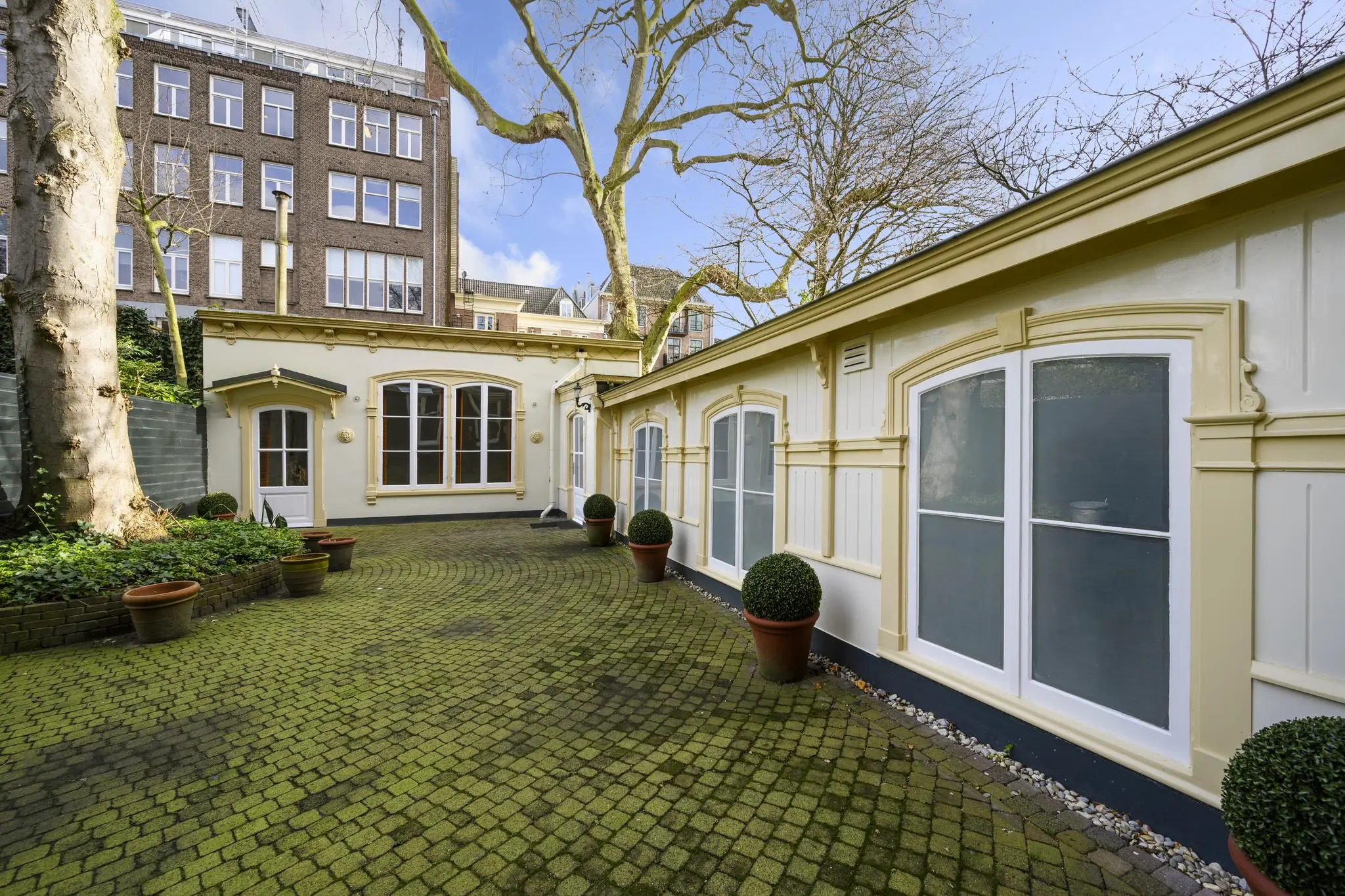 Binnenplaats met klassieke gevels en groen betegelde bestrating aan de Keizersgracht in Amsterdam.