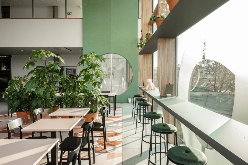 Moderne en lichte zitruimte aan de Hondiuslaan met groene accenten, grote ramen en veel planten.