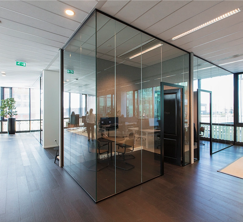 Modern kantoorinterieur aan de Herikerbergweg met glazen vergaderruimtes en houten vloer.