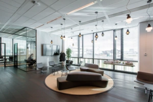 Moderne kantoorlounge aan de Herikerbergweg met designmeubels en grote raampartijen.