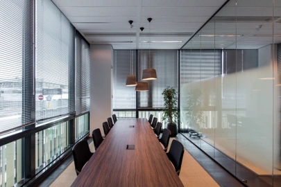 Moderne vergaderruimte aan de Herikerbergweg met lange houten tafel, glazen wanden en hanglampen.