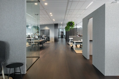 Moderne kantoorgang aan de Herikerbergweg met glazen vergaderruimtes en open werkplekken.