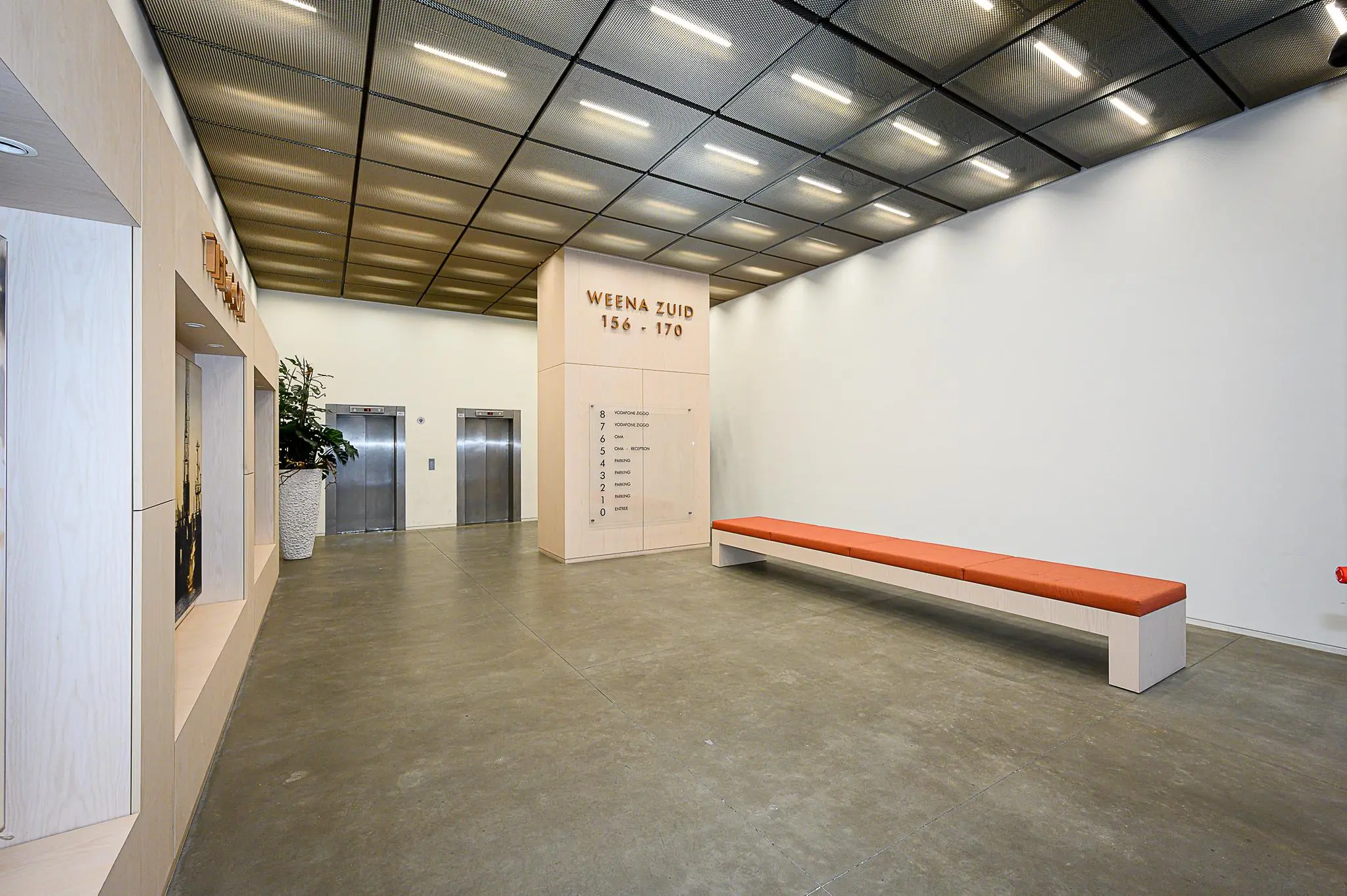 Moderne entreehal van het gebouw Weena Zuid 156-170 met liften, zitbank en een overzichtsbord.