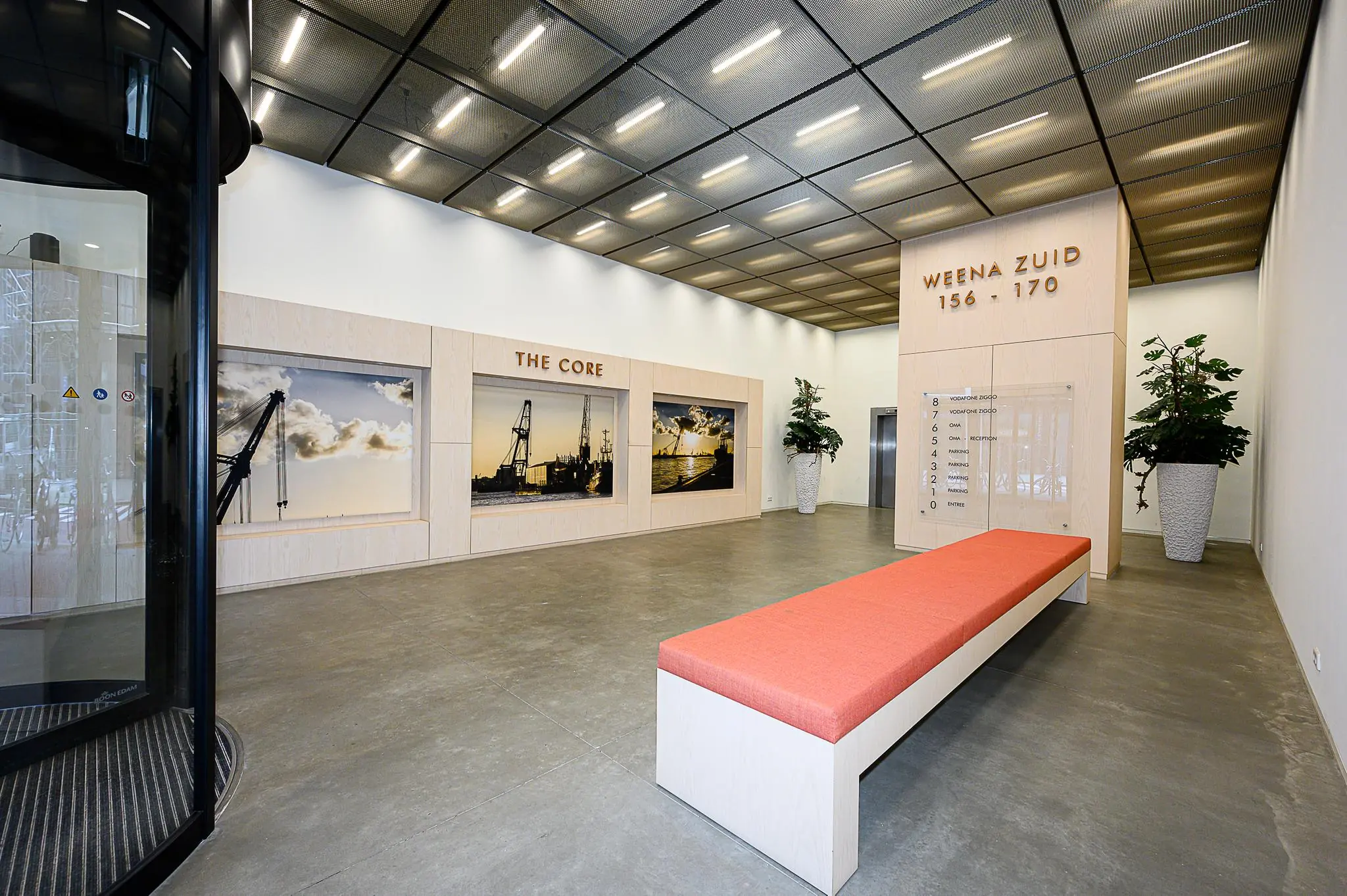 Moderne en strakke entreehal van kantoorpand Weena Zuid 156-170 met zitbank, wandfoto’s en routebord.