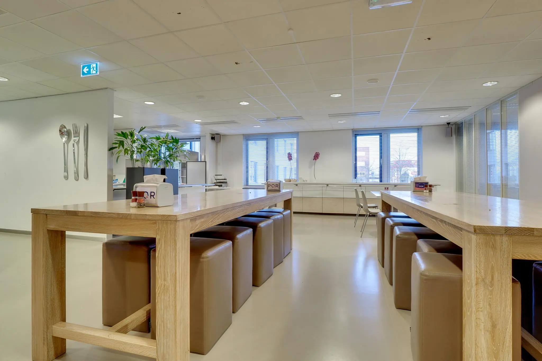 Moderne, open kantineruimte in Rijnzathe met houten tafels, leren krukken en grote ramen.