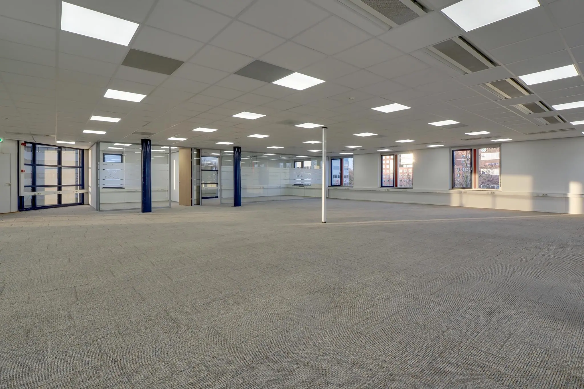 Ruime, leegstaande kantoorruimte in Rijnzathe met systeemplafond, tapijtvloer en glazen binnenwanden.