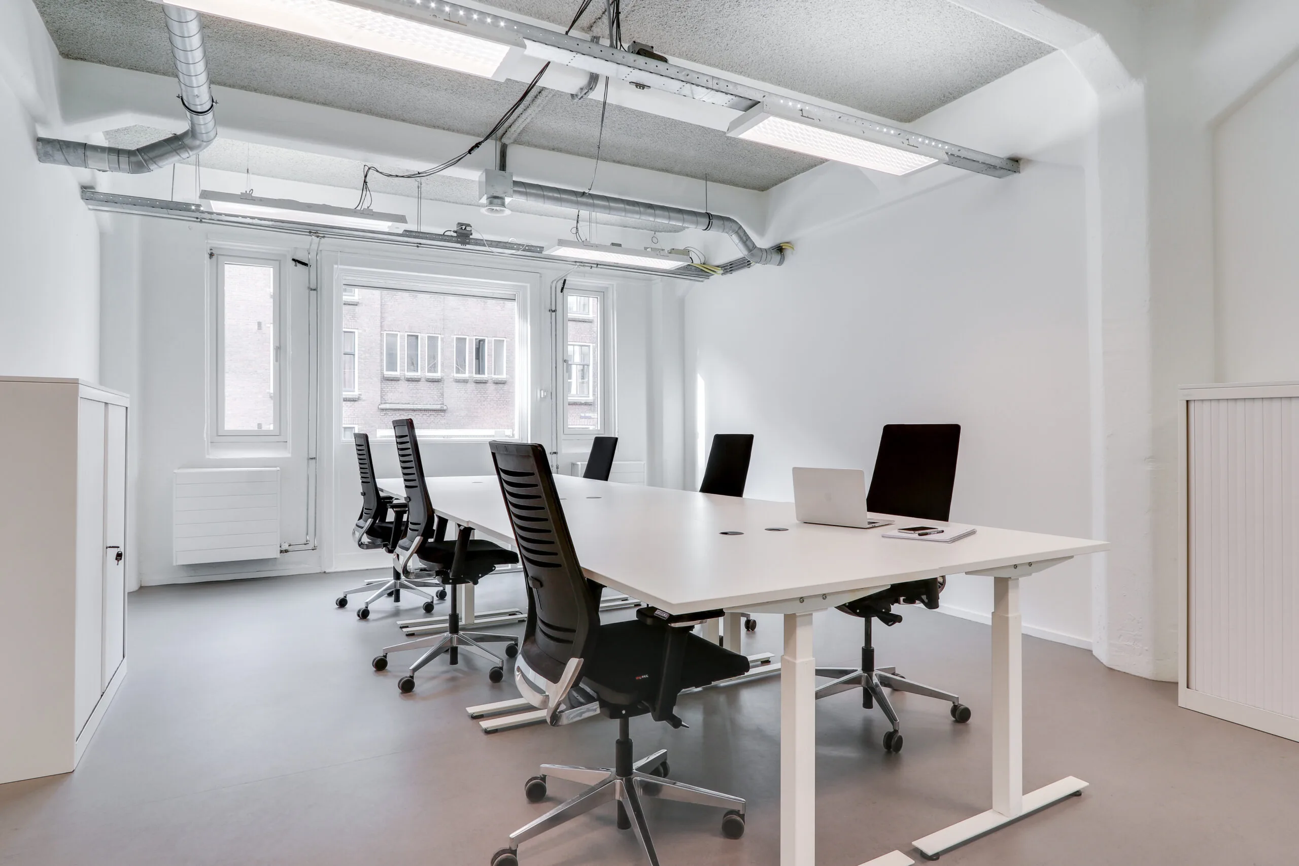 Moderne, minimalistisch ingerichte kantoorruimte in Amsterdam Houthavens met een lange vergadertafel en ergonomische bureaustoelen.