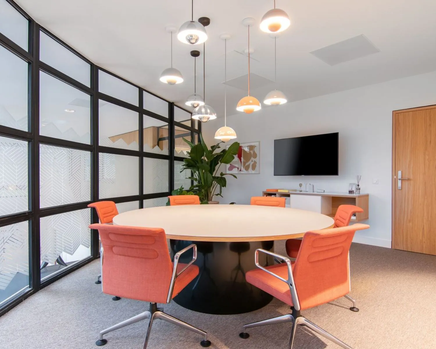 Moderne vergaderruimte in kantoor aan Schimmelt 2-16 in Eindhoven met ronde tafel, oranje stoelen en hanglampen.