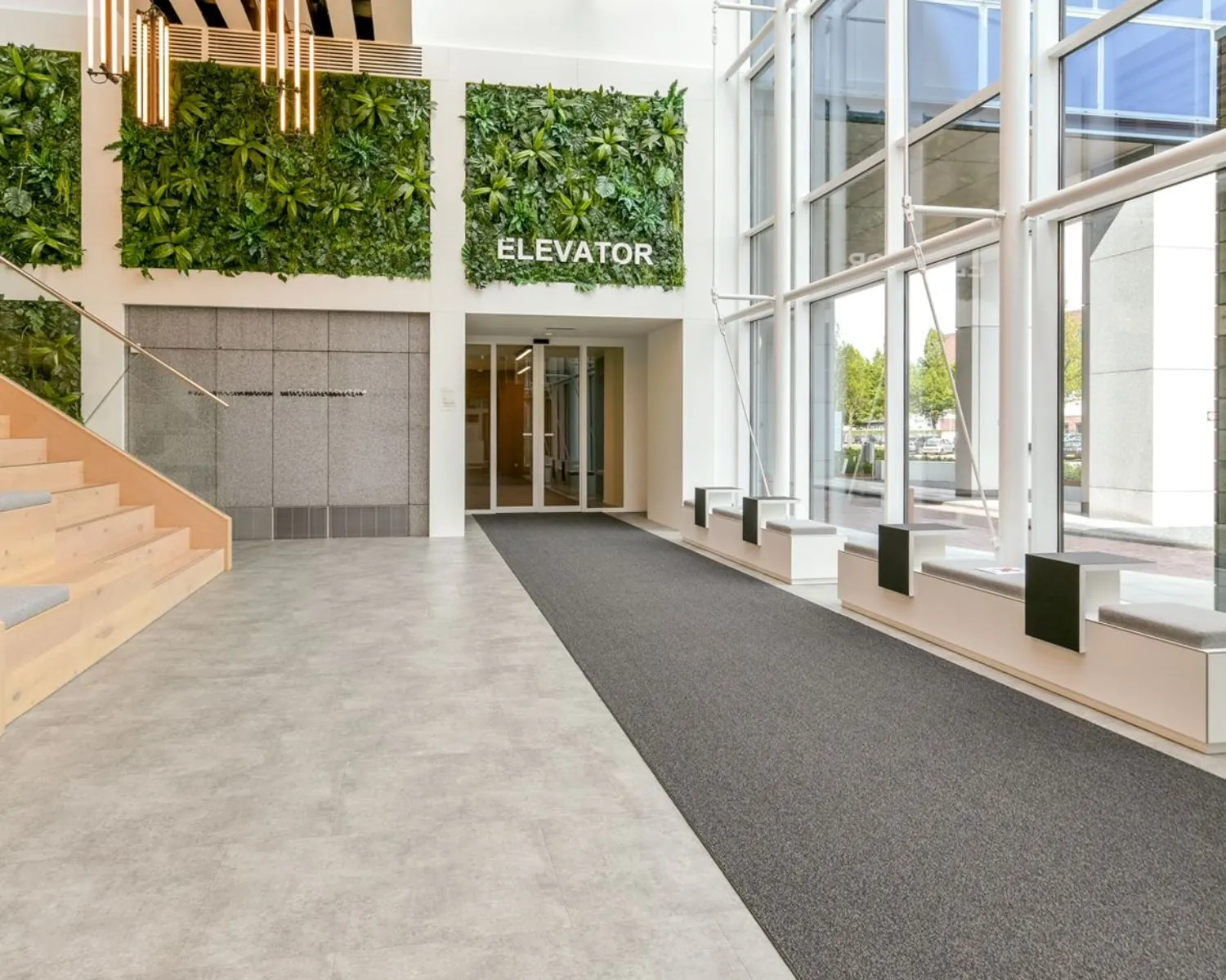 Moderne en lichte entreehal van het Coengebouw aan de Kabelweg 37 in Amsterdam met groene plantenwand en toegang tot de lift.