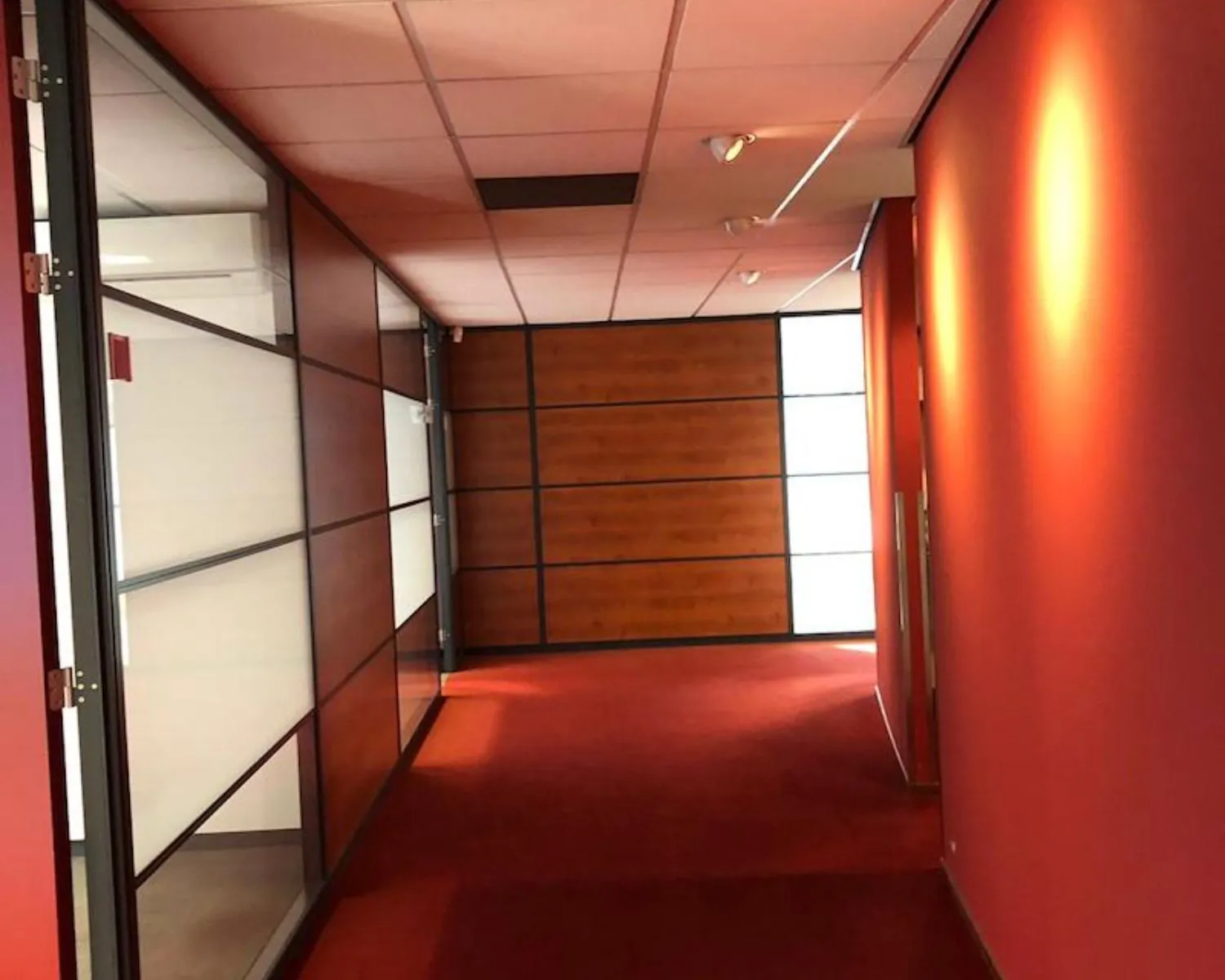 Gang met rode muren en vloerbedekking in kantoorruimte aan de Reeuwijkse Poort 114 in Reeuwijk.