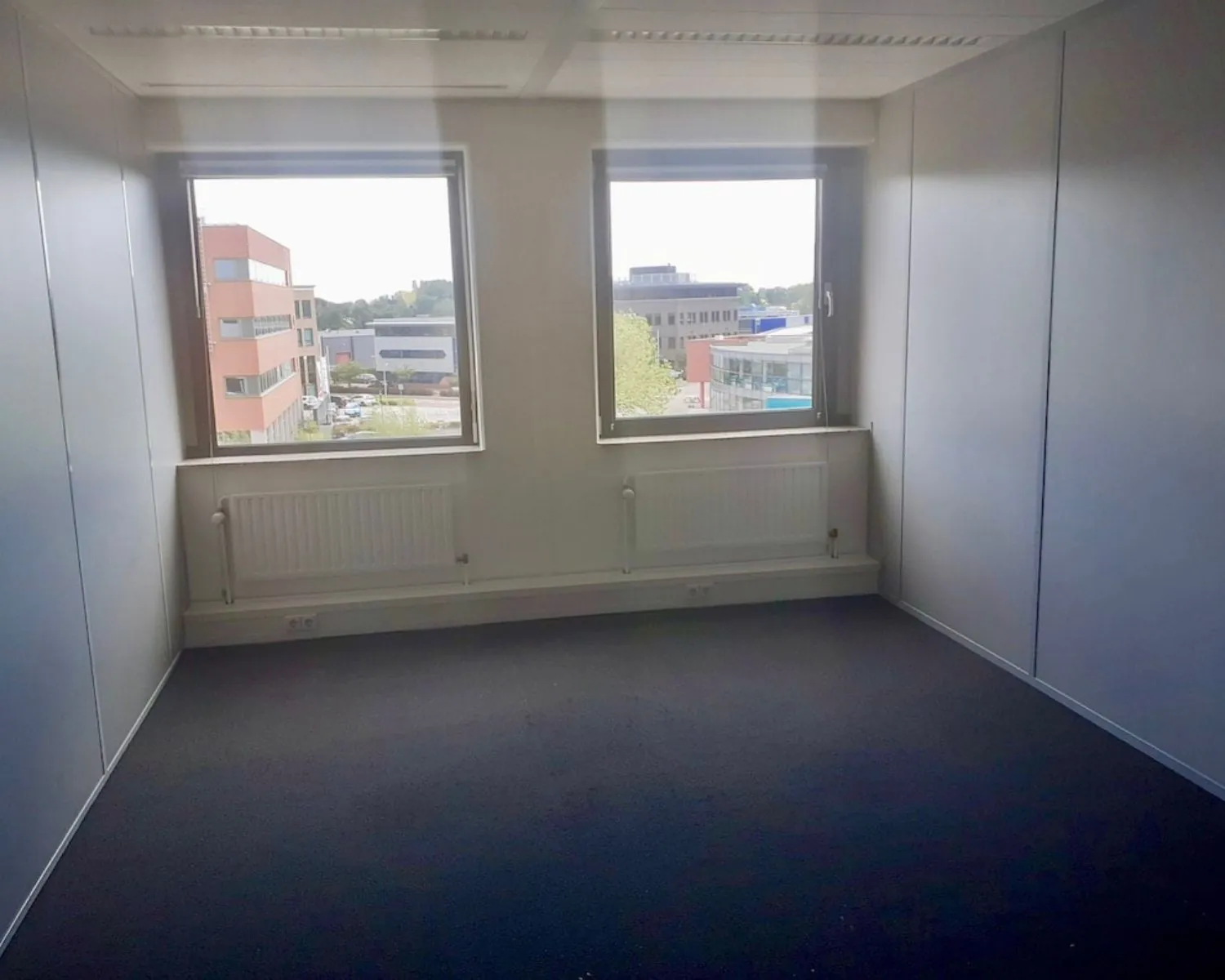 Leegstaande kantoorruimte met twee ramen en uitzicht op bedrijventerrein aan de Hardwareweg in Amersfoort.